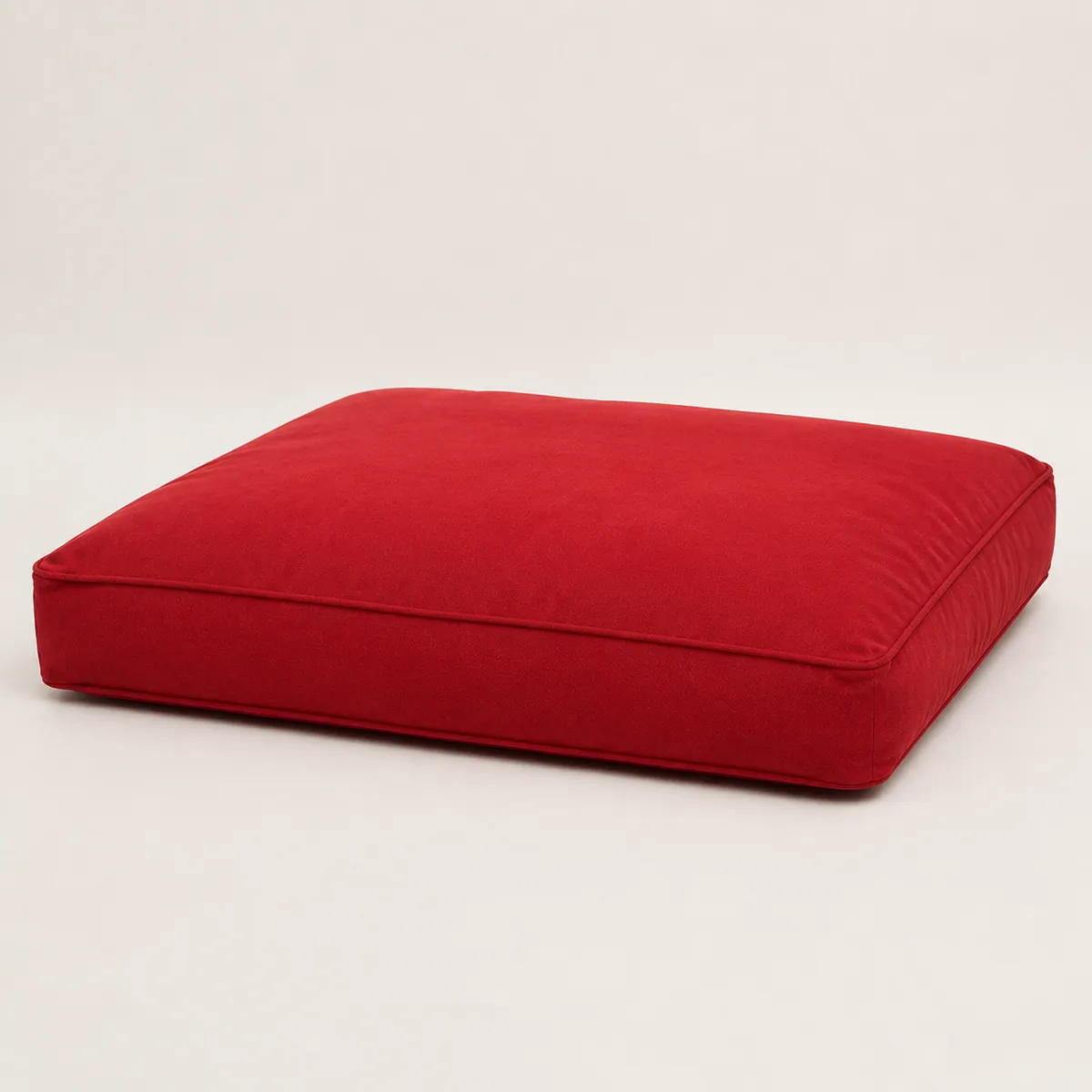 Red rectangular dog bed shown from a low side angle